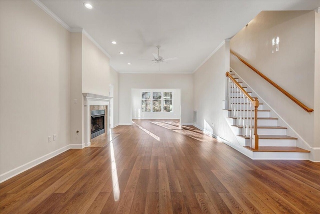 unfurnished living room with crown molding, ceiling fan, wood-type flooring, and a fireplace