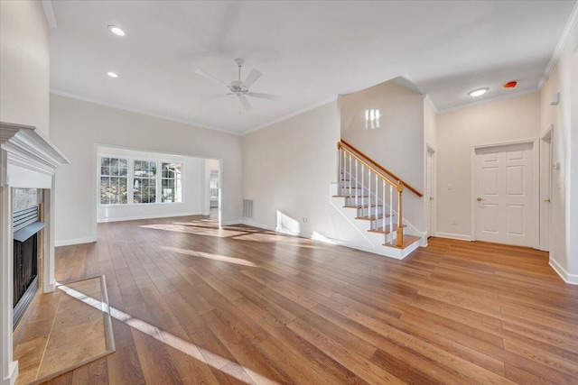 unfurnished living room with ornamental molding, a high end fireplace, and light hardwood / wood-style flooring