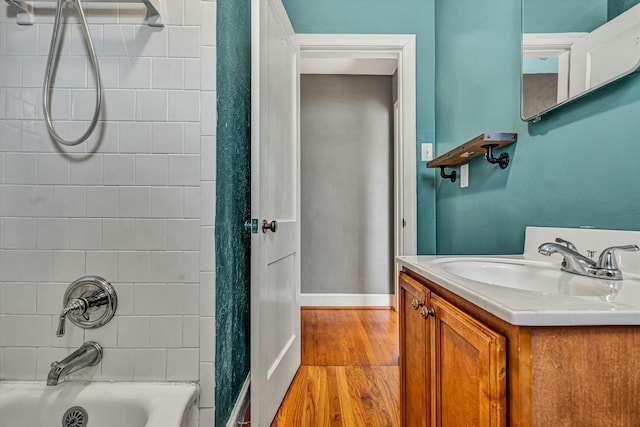 bathroom with tiled shower / bath combo, vanity, and hardwood / wood-style flooring