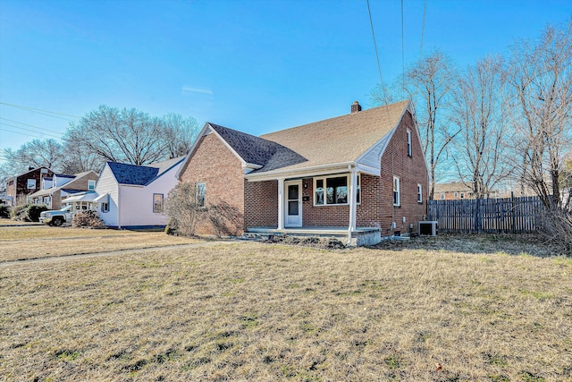 view of front facade featuring cooling unit, a front yard, and covered porch