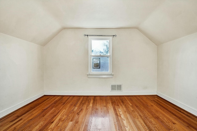 additional living space featuring wood-type flooring and vaulted ceiling