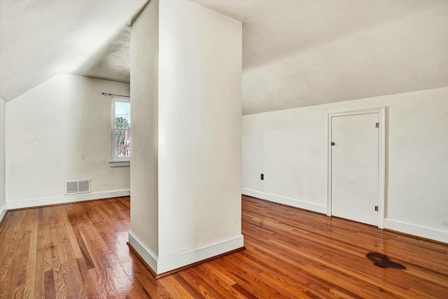 additional living space with wood-type flooring and vaulted ceiling