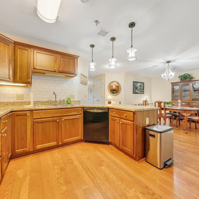 kitchen featuring pendant lighting, black dishwasher, sink, backsplash, and light wood-type flooring