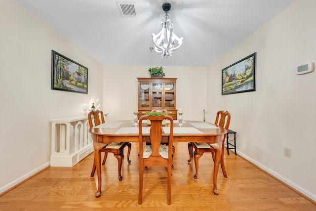 dining space featuring an inviting chandelier and light hardwood / wood-style flooring