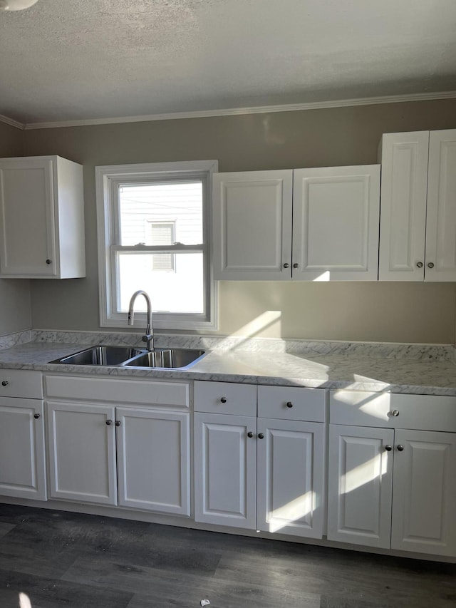 kitchen with sink, dark wood-type flooring, ornamental molding, and white cabinets