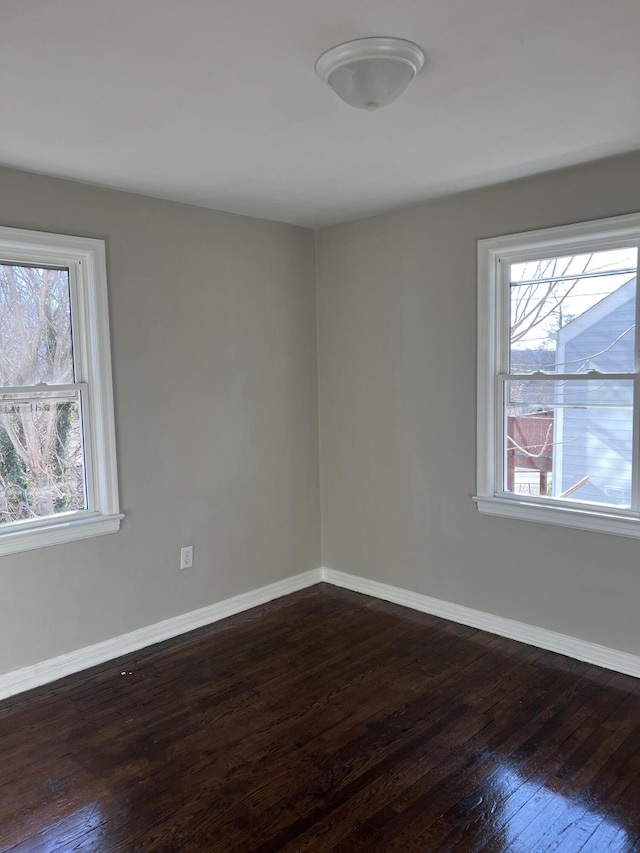 empty room with dark hardwood / wood-style floors and a wealth of natural light