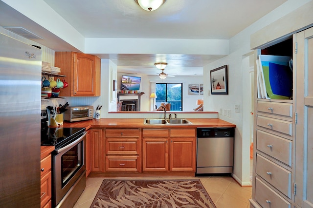 kitchen with sink, light tile patterned floors, ceiling fan, stainless steel appliances, and wood counters