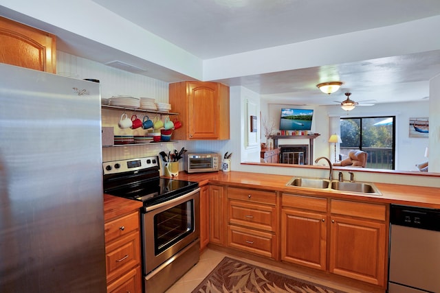 kitchen featuring sink, wooden counters, light tile patterned floors, kitchen peninsula, and stainless steel appliances