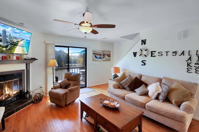 living room featuring a tiled fireplace, hardwood / wood-style flooring, and ceiling fan