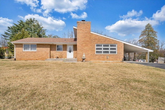 view of front of home featuring driveway, a front lawn, a carport, brick siding, and a chimney