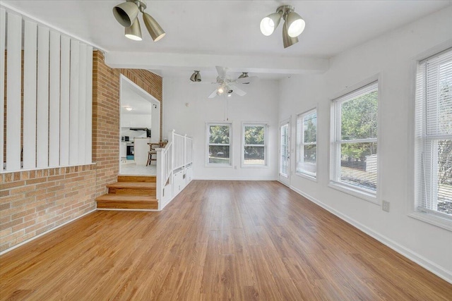 unfurnished living room featuring wood finished floors, a ceiling fan, baseboards, and a wealth of natural light
