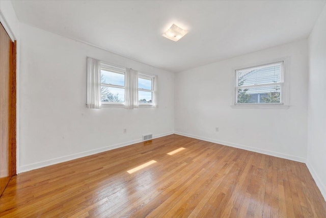 unfurnished room with light wood-style floors, visible vents, and baseboards