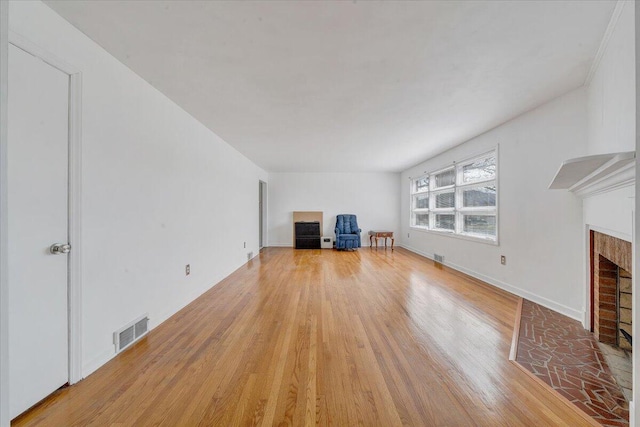 unfurnished living room with light wood-style floors, a fireplace, visible vents, and baseboards