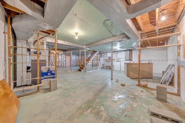 unfinished basement featuring stairs, water heater, and washing machine and clothes dryer