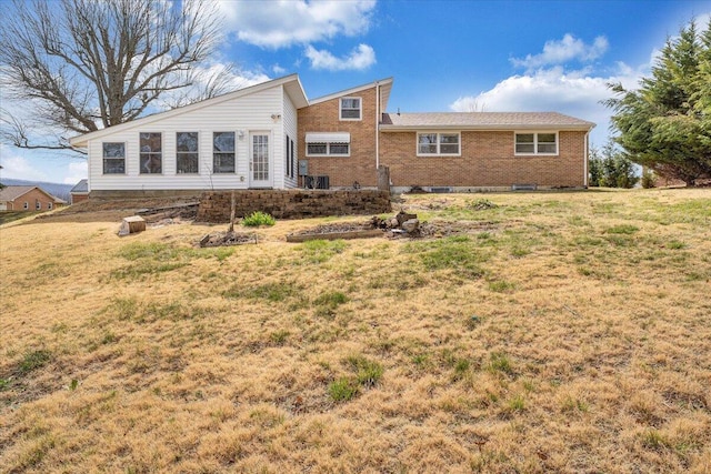 back of house featuring a yard and brick siding