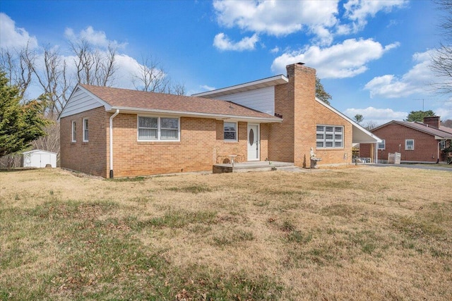 back of property featuring brick siding, a lawn, a chimney, a storage shed, and an outbuilding