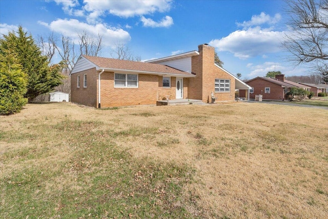 back of property featuring an outbuilding, a yard, brick siding, and a chimney