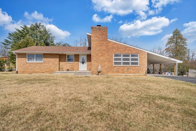 view of front of home featuring driveway, a chimney, a carport, a front lawn, and brick siding