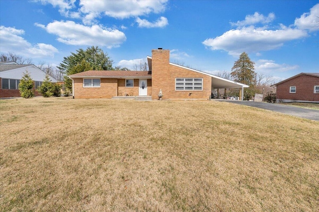 view of front facade with brick siding, a carport, a chimney, and a front lawn