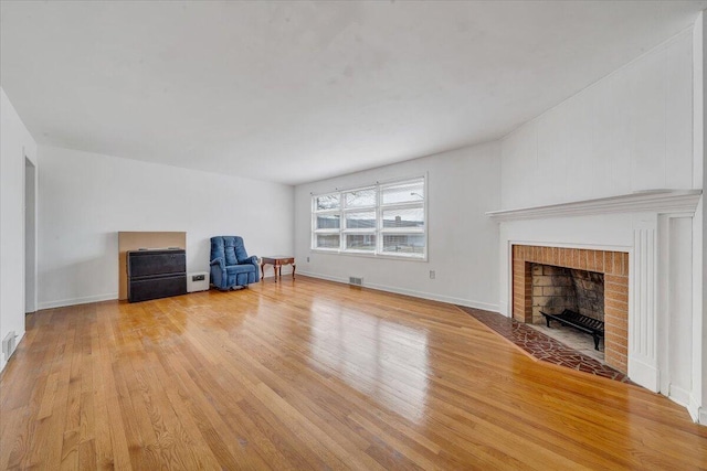 unfurnished living room featuring visible vents, a brick fireplace, baseboards, and light wood-style floors