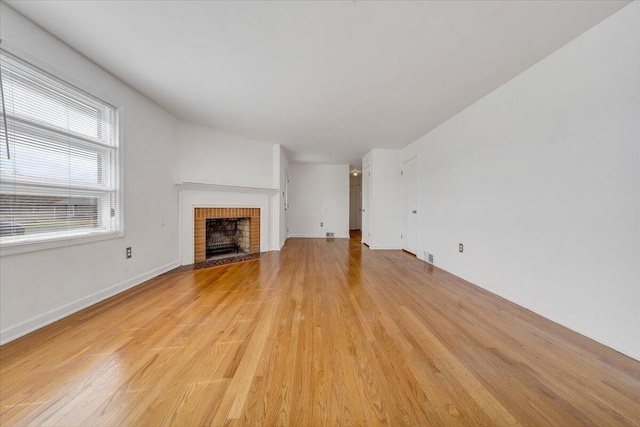 unfurnished living room featuring visible vents, baseboards, light wood-style flooring, and a fireplace