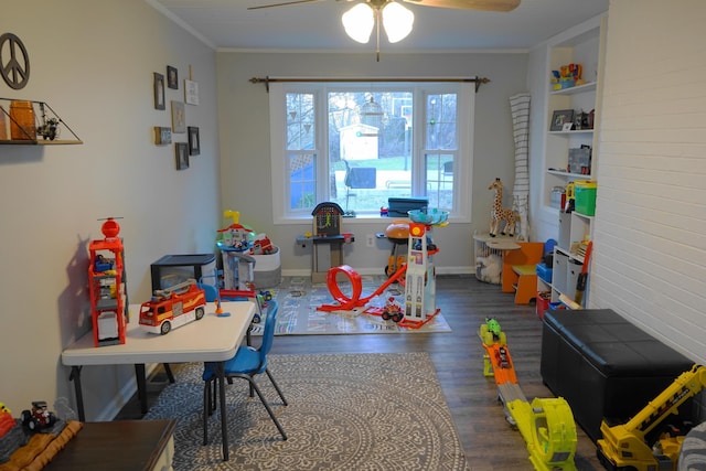 playroom with dark hardwood / wood-style flooring, crown molding, built in features, and ceiling fan