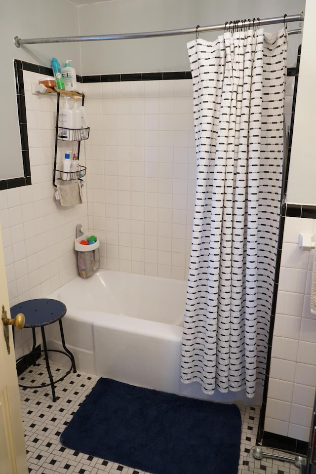 bathroom with shower / bath combination with curtain, tile patterned flooring, and tile walls