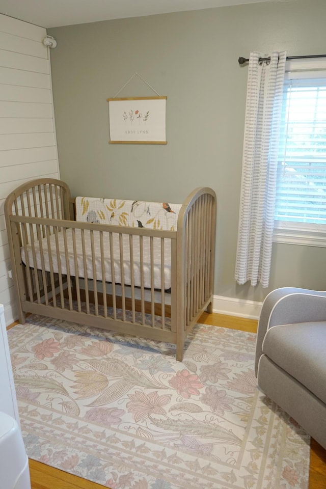 bedroom with wood-type flooring and a nursery area