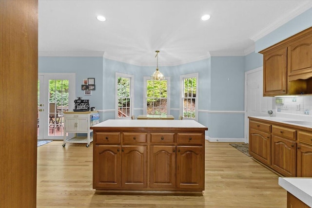 kitchen featuring decorative light fixtures, ornamental molding, light hardwood / wood-style floors, and a kitchen island