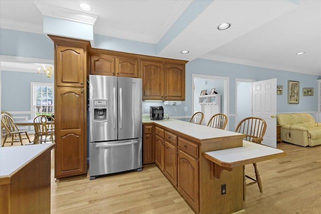 kitchen featuring stainless steel refrigerator with ice dispenser, a kitchen breakfast bar, kitchen peninsula, and light hardwood / wood-style floors