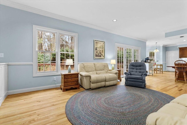 living room featuring french doors, ornamental molding, a notable chandelier, and light hardwood / wood-style flooring