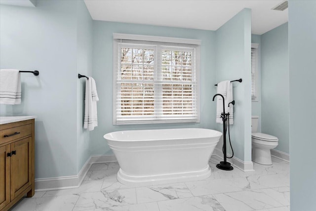 bathroom featuring a washtub, vanity, and toilet