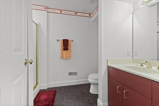 bathroom with vanity, a shower with door, and toilet