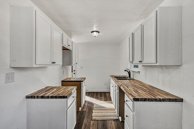 kitchen featuring dark hardwood / wood-style flooring, sink, wood counters, and white cabinets