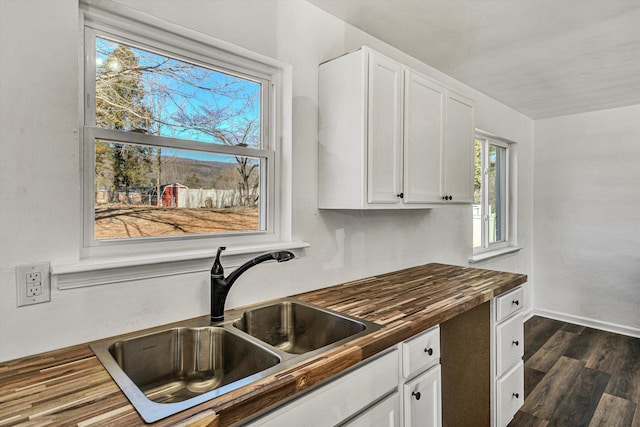 kitchen featuring butcher block counters, sink, dark hardwood / wood-style floors, and white cabinets