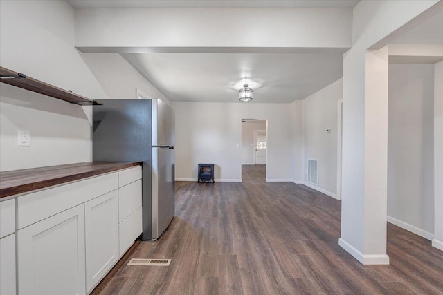 kitchen with dark hardwood / wood-style floors, white cabinetry, stainless steel refrigerator, and wood counters