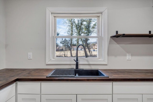 room details with white cabinetry, butcher block countertops, and sink