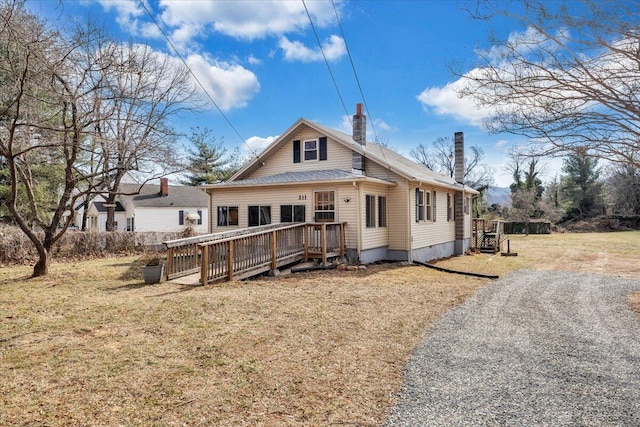 back of property featuring a lawn and a deck