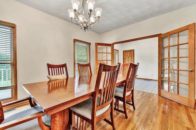 dining space with light hardwood / wood-style flooring and a chandelier