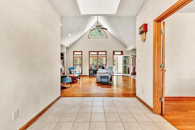 corridor featuring light tile patterned floors and high vaulted ceiling