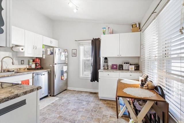 kitchen featuring lofted ceiling, sink, appliances with stainless steel finishes, white cabinetry, and tasteful backsplash