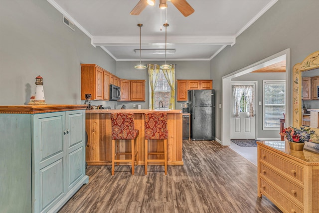 kitchen featuring dark hardwood / wood-style floors, decorative light fixtures, sink, a center island, and black fridge