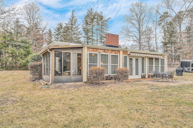 rear view of house with a yard, a patio area, and a sunroom