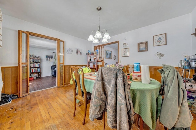 dining room featuring a wainscoted wall, light wood-style flooring, and an inviting chandelier