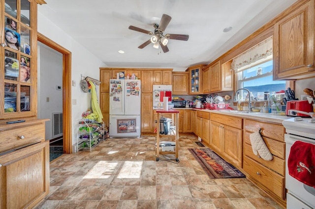 kitchen with white appliances, visible vents, glass insert cabinets, light countertops, and a sink