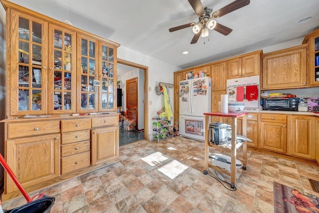 kitchen featuring ceiling fan, oven, a toaster, freestanding refrigerator, and glass insert cabinets