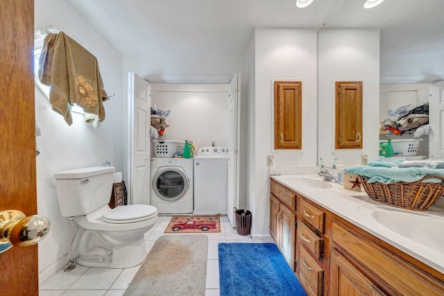 bathroom with washing machine and clothes dryer, double vanity, toilet, a sink, and tile patterned flooring