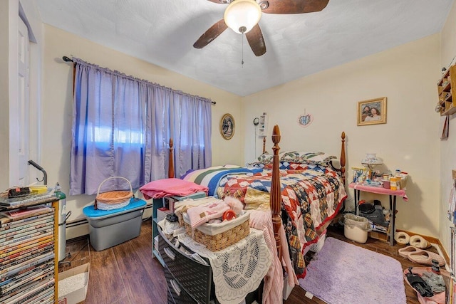 bedroom featuring baseboard heating, wood finished floors, and a ceiling fan