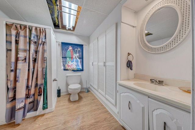 bathroom featuring a closet, toilet, vanity, wood finished floors, and baseboards