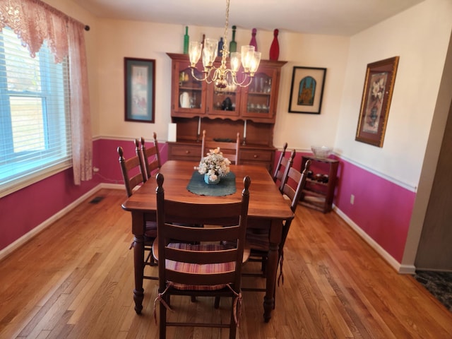 dining space with hardwood / wood-style flooring and a chandelier